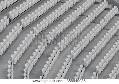Rows Of White Empty Plastic Seats In A Stadium.