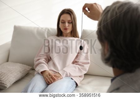 Psychotherapist Using Pendulum During Hypnotherapy   Session In Office