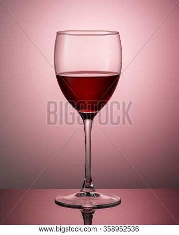 A Glass Of Red Wine On A Dark Surface With A Reflection