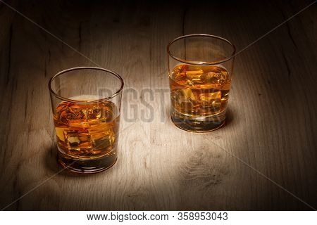 A Glass Of Whiskey With Ice Cubes On A Wooden Table. Selective Focus.