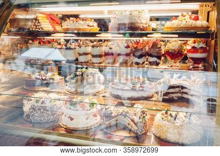 Assortment Of Desserts On Cafe Showcase. Variety Of Cakes Tiramisu Pies With Different Flavours Frui