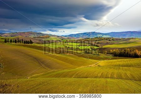 Picturesque hills of the legendary Tuscany. Agritourism. Rural farms. Smooth rows of plowed fields and meadows. Beautiful Italy. The concept of active, rural and photo tourism