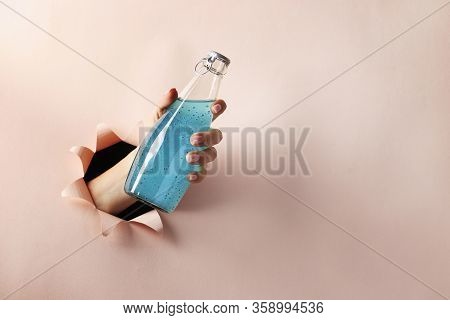 Bottle Blue Bright Drink With Basil Seeds Or Falooda Seeds In A Female Hand Through A Round Hole In 