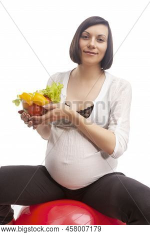 Pregnancy Concepts. Portrait Of Caucasian Brunette Woman In White Shirt Sitting On Big Fitball While