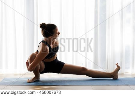 Young Woman In Skandasana Yoga Pose Doing Her Morning Yoga Routine