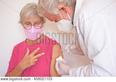 Doctor Giving Injection To Senior Caucasian Woman, Female Receiving Third Booster Of Covid 19 Vaccin