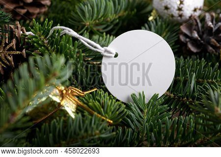 Christmas Round White Tag Mockup With White Cord, Close Up On Natural Fir Tree Branch, With Cones An