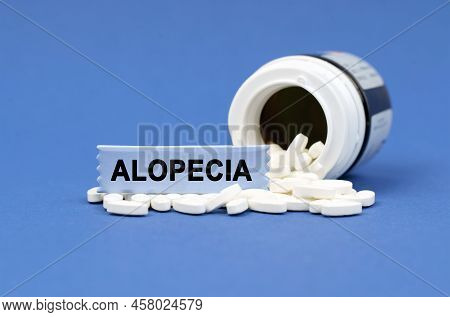 Medical Concept. On A Blue Surface Lies A Jar Of Pills And A Sign With The Inscription - Alopecia