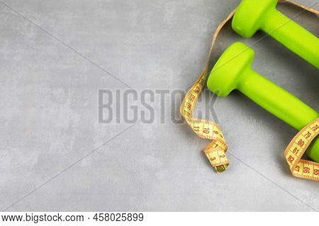Dumbbells, Measuring Tape On A Gray Textured Background. Fitness, Sports Nutrition