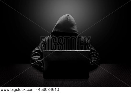 Hooded Computer Hacker Stealing Information With Laptop