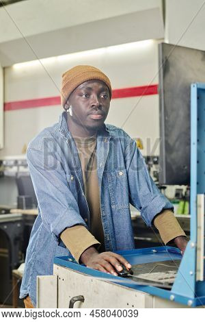 African Young Operator Looking At Monitor And Choosing Program During His Work At Computer Machine