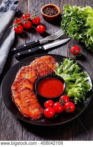 Grilled Slices Of Pork Loin Marinated In Paprika Based Sauce On Black Plate With Fresh Tomatoes And 
