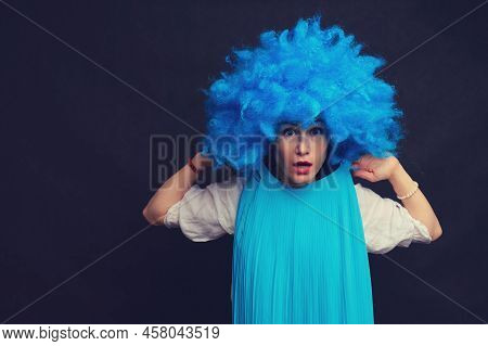 Woman In Funny Wigs Give Performance On A Studio Black Background. Showing A Humorous Show On A Dark