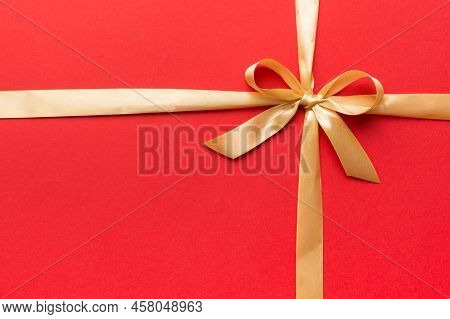 Top View Of Gold Ribbon Rolled And Yellowbow Isolated On Colored Background. Flat Lay With Copy Spac