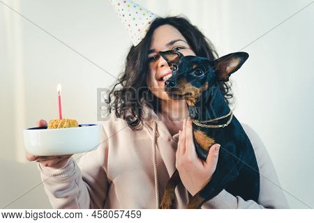 Happy Young Girl Giving Homemade Cake To Her Dog, Indoors