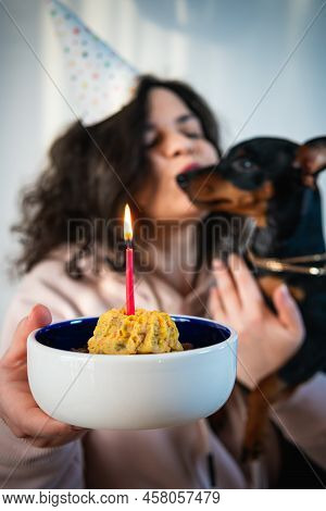 Happy Young Girl Giving Homemade Cake To Her Dog, Indoors. Concept Of Childfree By Choice And Celebr