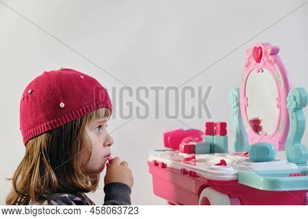 Pretty Little Girl Playing With Cosmetics Near Dressing Table In The Room. 2 Year Old.