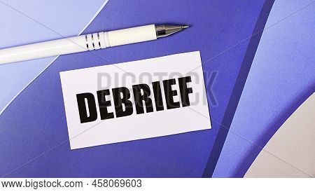 On A Lilac And Purple Background, A White Card With The Text Debrief And A White Pen. Layered Backgr