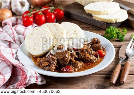 Czech Traditional Goulash With Breaded Dumpling And Onion On White Plate On Wooden Table
