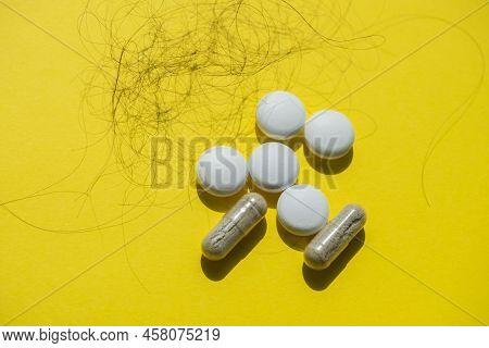 Pills And Fallen Hair On A Yellow Background. Baldness And Hair Loss Problem