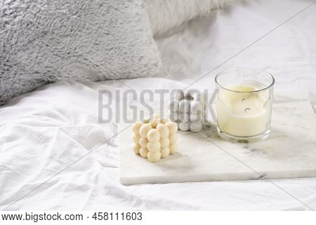 Three Candles - Bubble Candles And White Candle In Glass Jar With Silver Lid On Marble Tablet On Whi