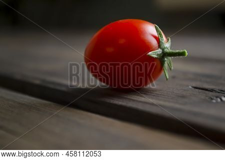 Tomt Cherry Near On A Wooden Table, Shooting From The Side. A Lonely Cherry Tomato. Tomato Cream. Wo