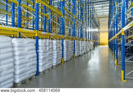 Interior Of A Modern Warehouse Storage Of Retail Shop With Pallet Truck Near Shelves. Rows Of Steel 