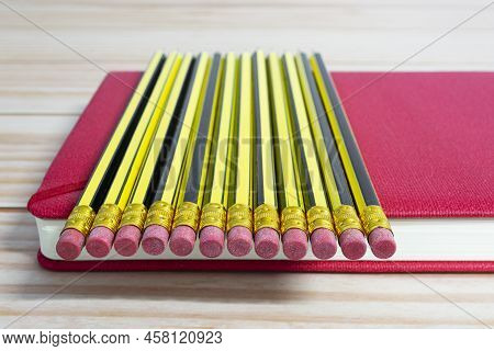 Wooden 2b Pencils Lying On Red Note Book On Wooden Desk. Copy Space.