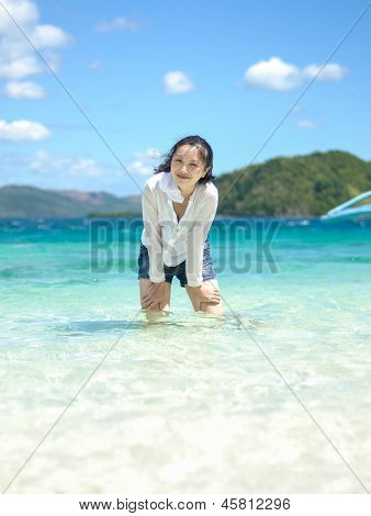 smiling young girl stands in shallow water