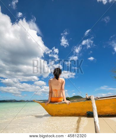 young girl sitting on boat on beach