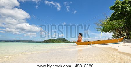 young girl sit on boat on white beach