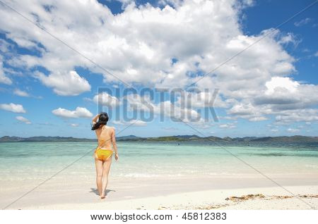 young girl stands in shallow water looking at horizon