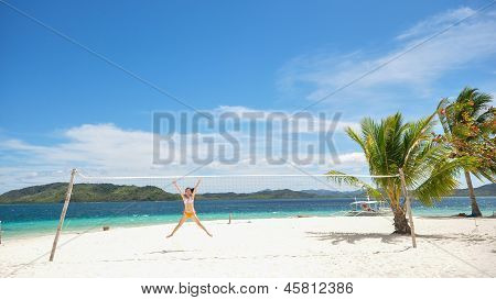 young girl jumps under volleyball net on white beach