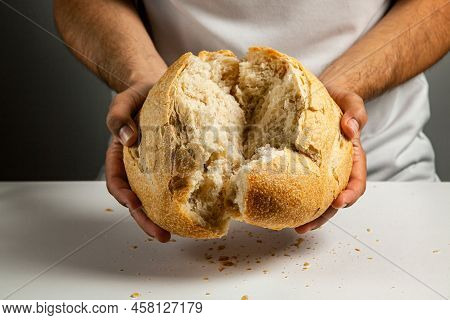 Mens Hands Break A Loaf Of Round Wheat Bread Made With Sourdough, Showing The Inner Texture.