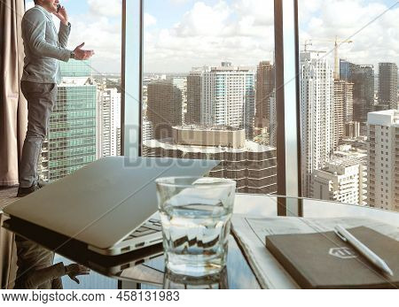 Man At The Panoramic Window Talking On The Phone Indoors