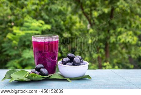 Jamun Or Black Plum Juice In A Glass With Fruit In A Bowl With Leaves Isolated On Wooden  Background