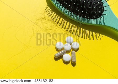 Green Comb, Pills And Fallen Hair On A Yellow Background. Baldness And Hair Loss Problem