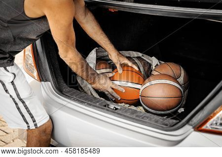 Close-up Image Of Man's Hands Taiking The Basketball Balls From Trunk Of A Car