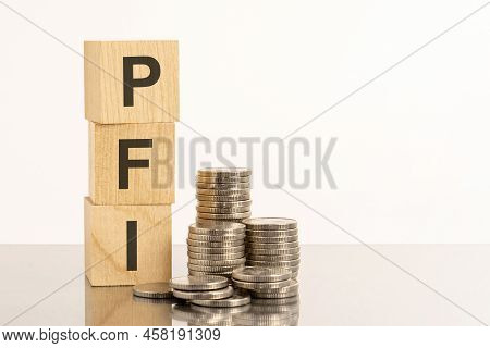 Wooden Blocks With The Text Pfi. Cubes And Coins Reflected From The Surface. Pfi - Short For Private