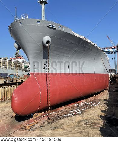 Dry-cargo Ship In Dry Dock For Repairs And Maintenance At A Shipyard. Stern Bottom Of The Ship Layin