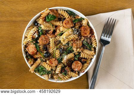 Rotini Pasta Served With Italian Sausage And Sauteed Spinach.