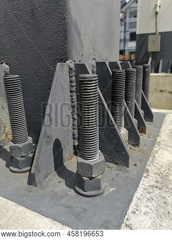 Bolts And Nuts On The Cement Base. Several Gray Double Bolts Are Firmly Fixed To A Steel Column To A