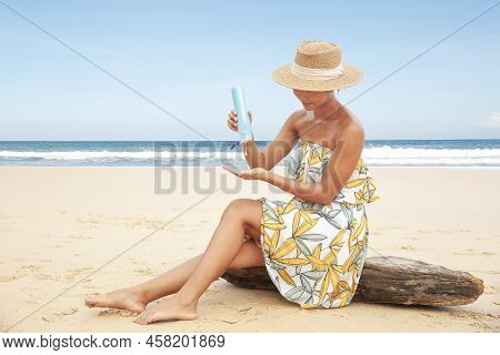Woman Pouring Applying Sunblock Cream Lotion On Beach For Broad Spectrum Uva, Uvb Sun Protection