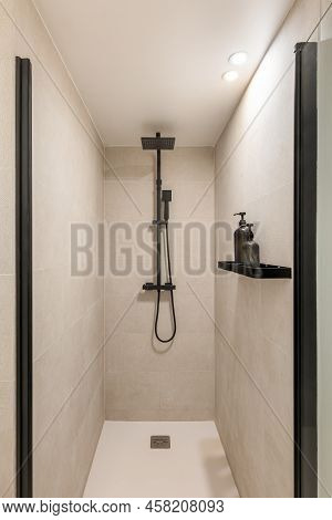 Modern Shower Zone With Black Rain Head And Hand Held Shower. Beige Tiles In The Bathroom.