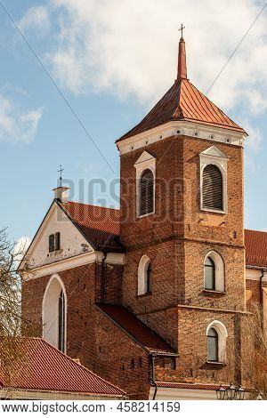 Vertical Photo Of Brown Brick Tower Of Gothic Style Basilicia At Sunny Day. Kaunas Parochial Archcat