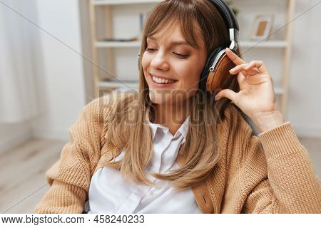 Cute Happy Young Blonde Student Lady Freelancer In Warm Sweater Wear Headphones Enjoy Fav Songs Sitt