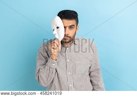 Serious Bearded Businessman Removing White Mask From Face Showing His Strict Expression, Pretending 