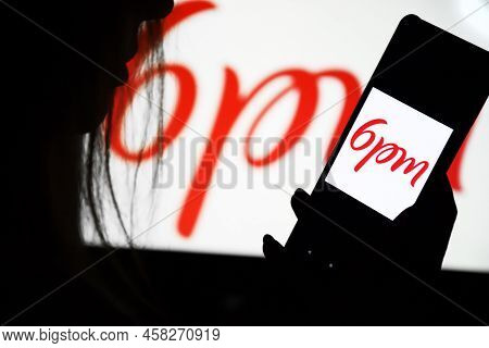 A Phone With A 6pm Screen In The Hands Of A Young Girl Against The Background Of A Monitor. Selectiv