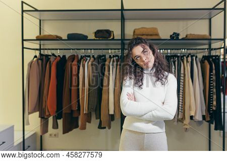 Upset And Sad Young Woman Standing In A Clothing Store In A Shopping Center, Hands Folded, Dissatisf