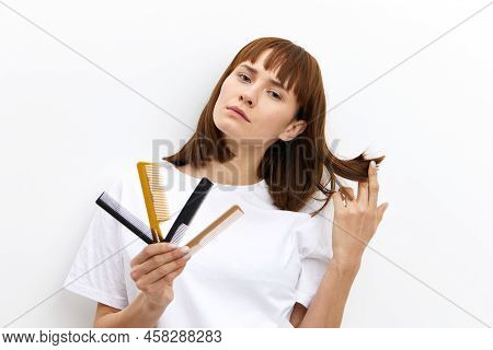A Sweet, Pleasant Woman With A Beautiful Hairstyle Holds A Lot Of Different Combs In One Hand, And P